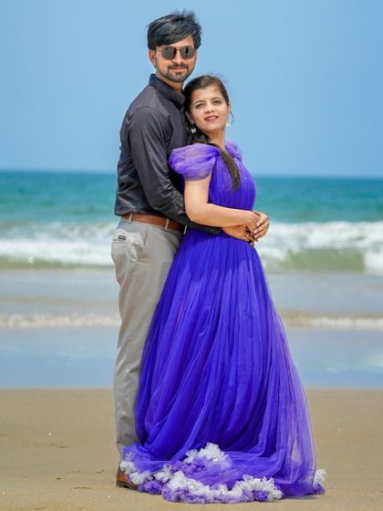 A bright and sunny pre-wedding photo on the beach. The royal blue gown with a ruffled trail is a vibrant and cheerful choice.