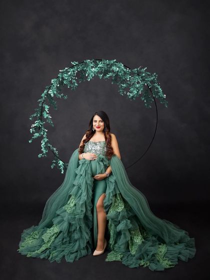 A full view of this stunning green gown, framed by a circular prop adorned with matching green leaves.