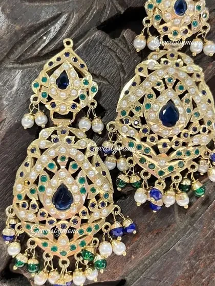 These Rajwadi-style earrings feature beautiful blue and green enamel work, known as meenakari, surrounded by pearls. They are designed to bring a touch of traditional Rajasthani grandeur to any bridal look.