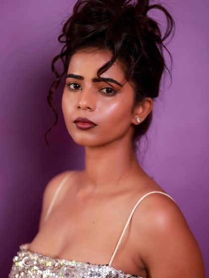 A striking close-up portrait in a silver sequin dress. The messy updo and bold lip create a look that is both glamorous and edgy.