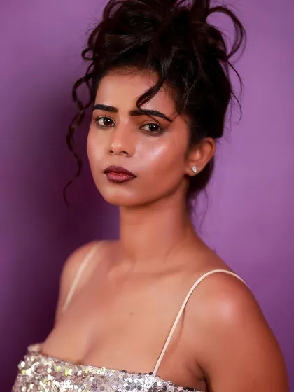 A striking close-up portrait in a silver sequin dress. The messy updo and bold lip create a look that is both glamorous and edgy.