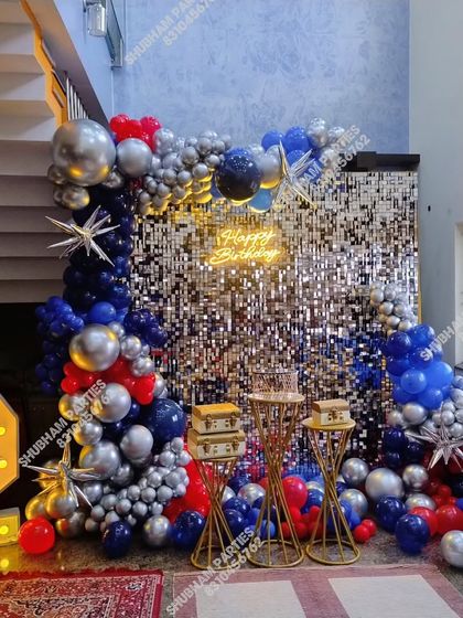 A bold and striking party decoration with a silver sequin wall and a balloon arrangement in red, blue, and silver chrome.