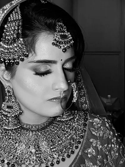 Another black and white portrait of the same bride, capturing a different angle. It highlights the intricate jewelry and the clean lines of her eye makeup and hairstyle.
