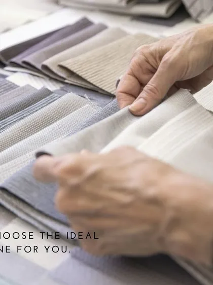 A client's hands exploring the texture and feel of different fabric books. The tactile experience is crucial in selecting the material for a custom-made garment.