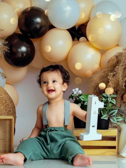 Celebrating turning one with a big smile. This little boy looks so proud next to the '1' sign in his charming bohemian cake smash setup.