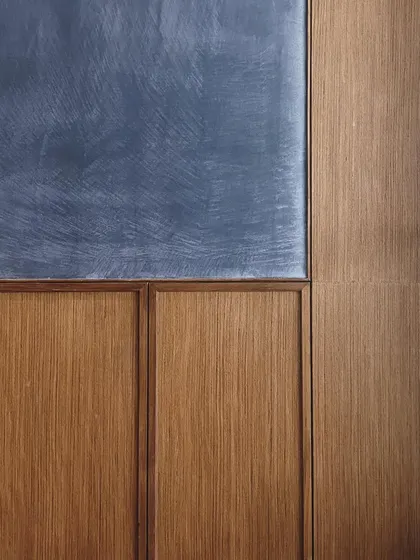 A study in texture and color, this image shows the junction of a blue lime-washed wall and wood wainscoting. The careful alignment and proportion of these elements is a hallmark of our design approach.