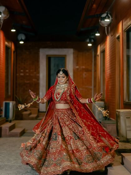 A bride's joyful twirl in a beautifully lit corridor. This dynamic shot captures her happiness and the stunning detail of her wedding lehenga.