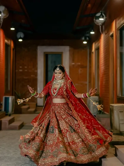A bride's joyful twirl in a beautifully lit corridor. This dynamic shot captures her happiness and the stunning detail of her wedding lehenga.