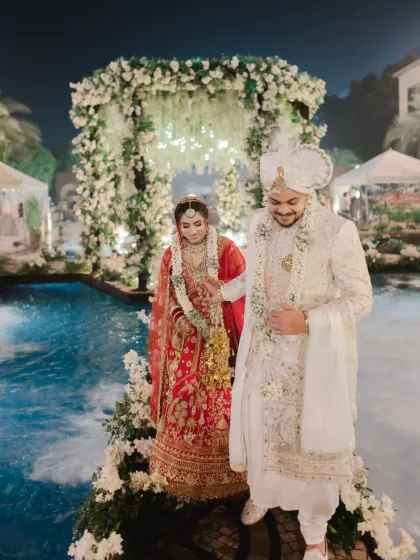 The couple walks hand in hand across a path built over the pool after their ceremony. This candid moment captures their happiness and the unique, stunning setup of their wedding venue.