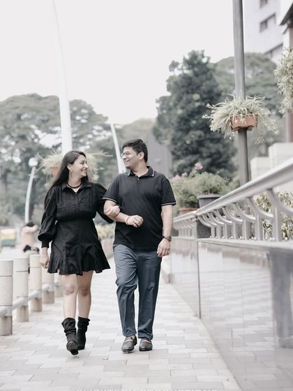 A full-length shot of a couple walking arm-in-arm down a city sidewalk, capturing a simple, happy moment.