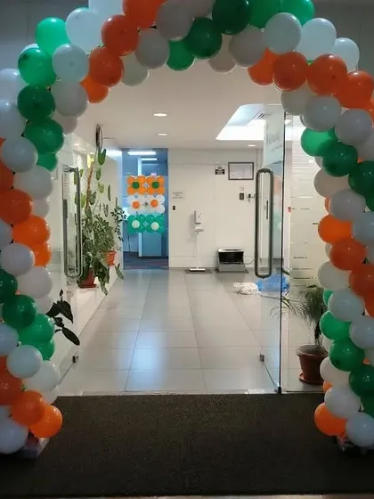 A balloon arch in the colors of the Indian flag (saffron, white, and green) for an Independence Day or Republic Day celebration at an office.