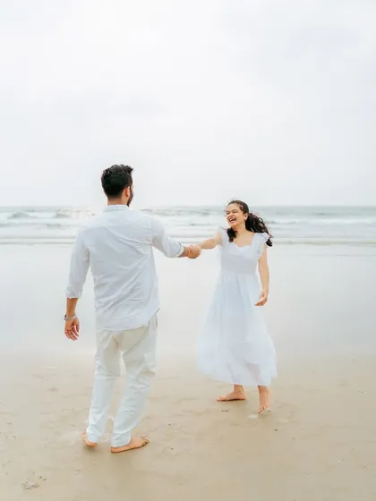 A joyful, candid shot of the couple dancing on the sand, their laughter echoing the carefree vibe of Goa.