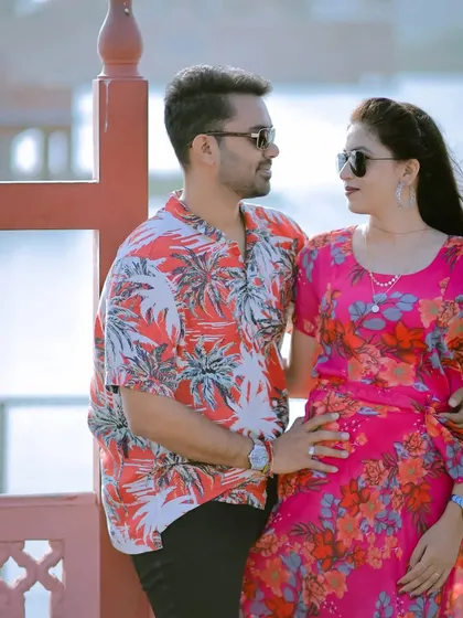 A stylish and relaxed pose against the railings by the lake. The couple's modern sunglasses and casual outfits give this shot a cool, contemporary vibe.