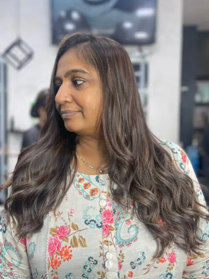 A happy client with her freshly colored and styled hair. The soft waves and natural-looking highlights create a beautiful, low-maintenance look.