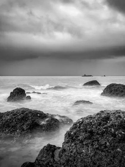 A moody, monochrome long exposure of the sea at Gokarna from 2017. The dark clouds and soft water create a dramatic and contemplative atmosphere.