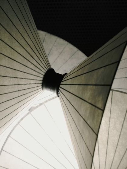 A detailed macro shot of the Serpentine Light, focusing on the point where the paper-like cones converge, revealing the thoughtful construction of the piece.