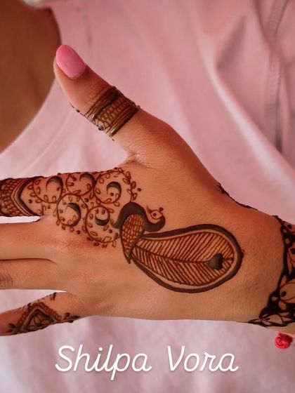 A simple and charming peacock feather design on the back of the hand, perfect for an engagement party or sangeet.