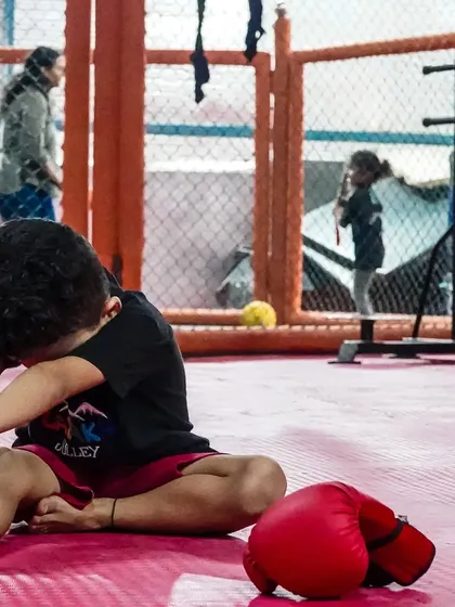 A quiet moment of stretching for one of our youngest members. With boxing gloves nearby, he's learning the discipline of preparing his body for training and cooling down afterward.