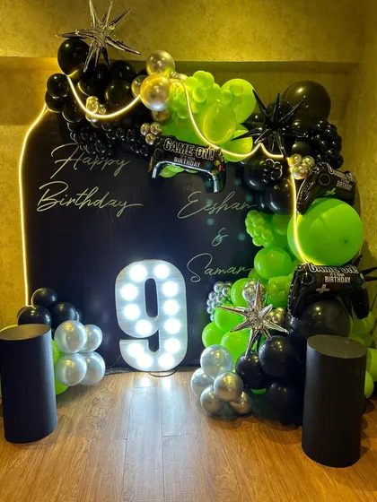 Another angle of the epic gaming party decor, showing the full setup with its glowing lights and bold colors. The two black plinths are ready for a cake or desserts, completing the party's focal point.