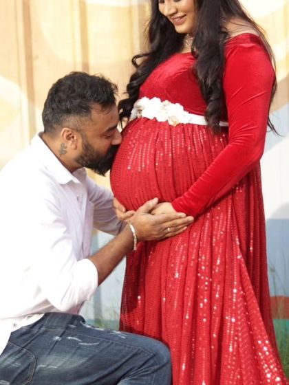 An intimate father-to-be moment captured during a maternity shoot. The rich red sequin gown adds a festive and celebratory feel to the photos.