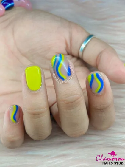 A bright and playful design featuring neon yellow nails and accent nails with wavy stripes of blue and yellow on a sheer base.