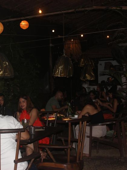 The cozy, intimate setting of our Goa pop-up at night, with warm lights and lush greenery creating a perfect atmosphere for a memorable meal.