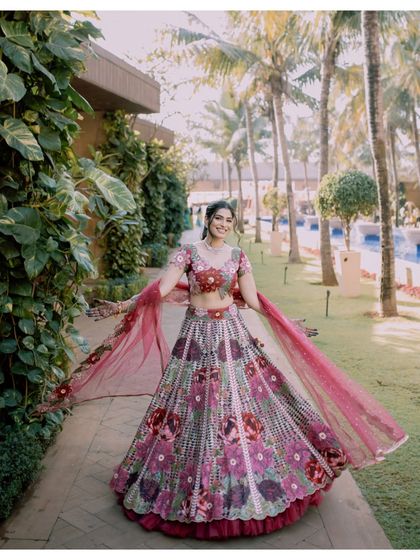 A bride twirls in her vibrant, floral lehenga in a lush garden setting. This photo is full of life, color, and happiness.