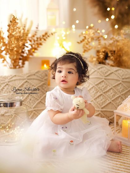 A candid moment of the birthday girl in a dreamy, light-filled setting, holding a small teddy bear. The soft focus and warm lights create a magical atmosphere.