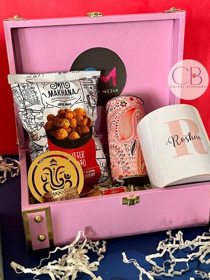Diwali vibes are in the air. This lovely pink trunk box is a perfect corporate gift, containing makhana, a customised mug, a can of iced tea, and a Ganesha T-light holder.
