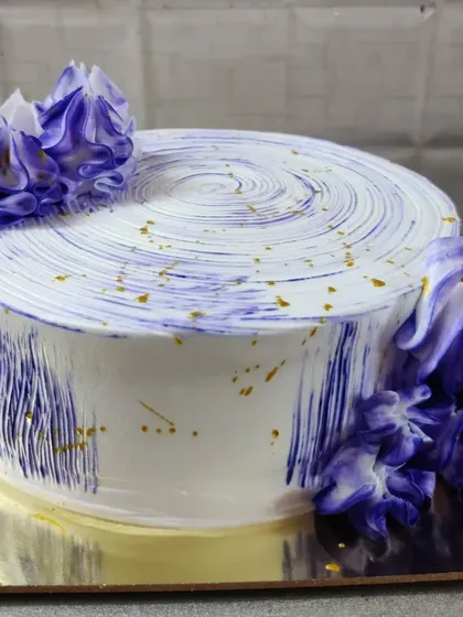 For a more modern look, I created this cake with an abstract purple brushstroke design against a clean white frosting. A few flecks of gold dust and piped purple flowers add a touch of artistic flair.