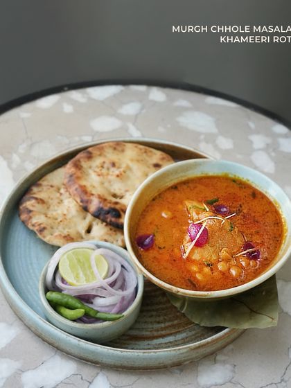Murgh Chhole Masala, a comforting dish of chicken and chickpeas in a flavorful gravy, served with soft Khameeri Roti. A perfect example of how we elevate traditional recipes for a refined dining experience.