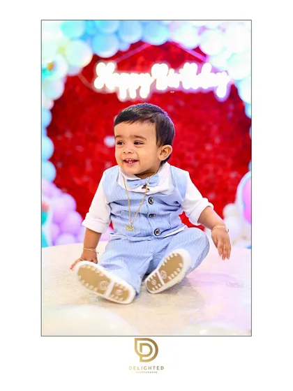A little prince celebrates his first birthday with a big smile, surrounded by festive balloons. This photo highlights my approach to capturing the pure joy of children's parties.