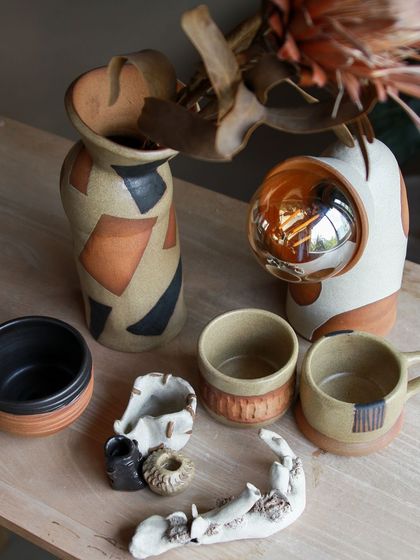 An artistic collection featuring an astronaut themed lamp, a carved ashtray, and a vase with bold, geometric patterns.