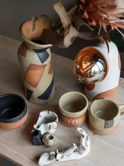 An artistic collection featuring an astronaut themed lamp, a carved ashtray, and a vase with bold, geometric patterns.