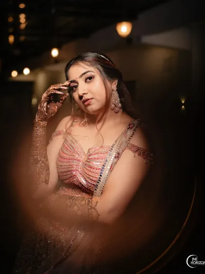 An artistic portrait of a client during her mehndi event, the lighting beautifully highlighting her features and the intricate henna on her hand.