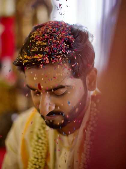 Another angle of the 'talambralu' ritual, focusing on the groom's joyful expression as he is showered with colorful rice by his bride.