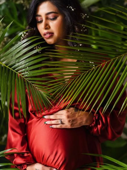 A lush, tropical-themed portrait with the mother-to-be framed by palm leaves.