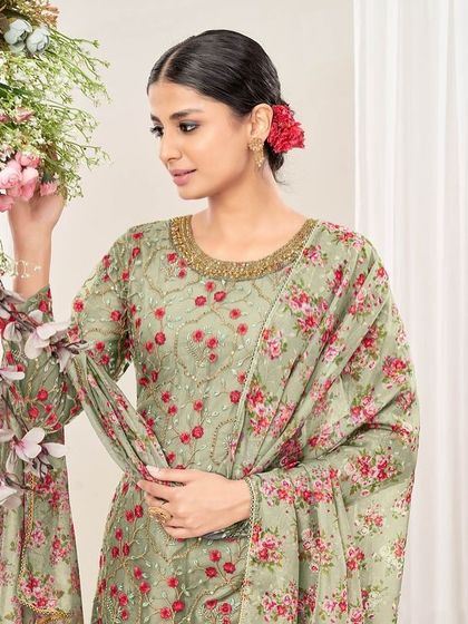 This pista green net suit is fresh and floral. The thread embroidery and printed dupatta with dhoti pants create a playful yet elegant look.