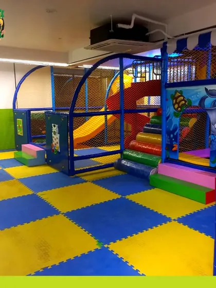 A wider perspective of the soft play area, showing the layout with its slides and climbing sections on a cushioned, interlocking floor.