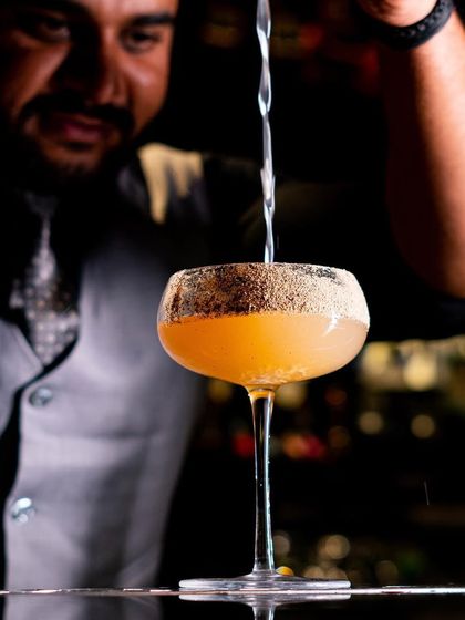 Each sip of our masterful mixology is a testament to the commitment and artistry that goes into every single creation. Here, a bartender pours a 'Black Gold' cocktail.