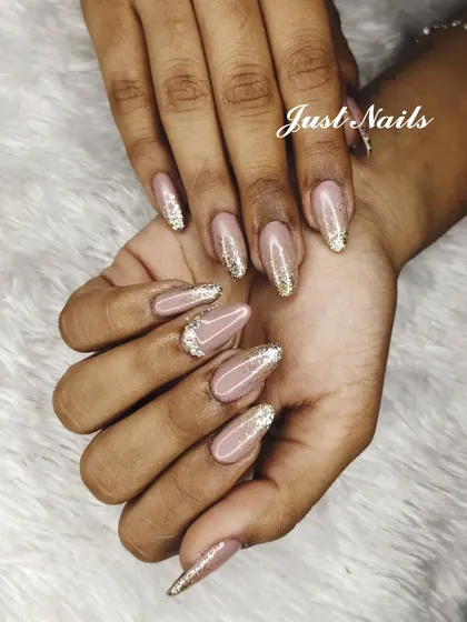 A chic design with a nude base and sparkling gold glitter applied in a reverse French or cuticle-focused style.