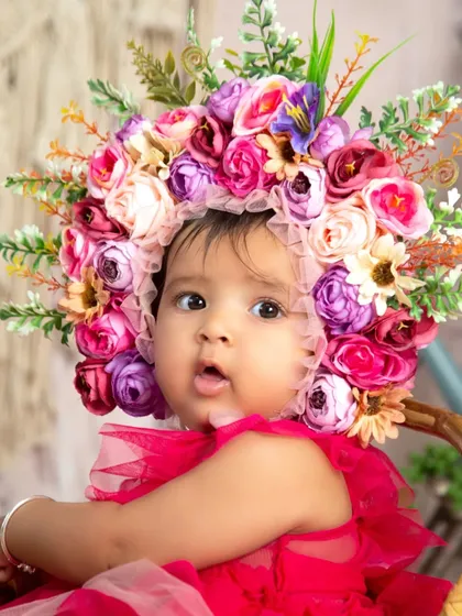 A close-up portrait highlighting the delicate details of a half-birthday photoshoot. The intricate floral bonnet and the baby's sweet expression make for a timeless and beautiful memory.