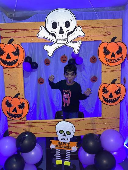 A young guest in vampire makeup poses for a picture in the Halloween frame. I provide themed props and backdrops to make every party memorable.
