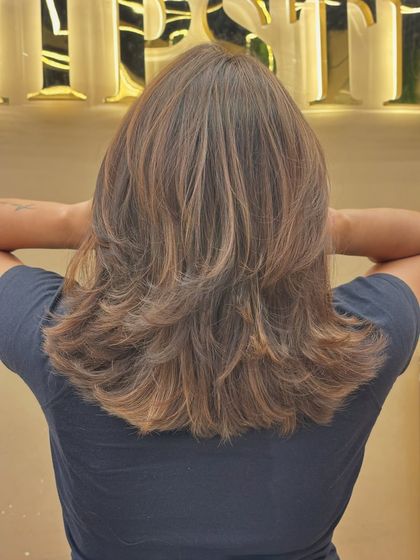This back shot shows off a beautiful, medium-length layered cut with a fresh, even color. The style is timeless and easy to maintain, with a healthy, glossy finish.