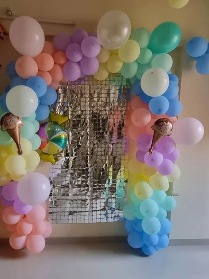 A soft and dreamy pastel rainbow balloon arch. This setup is perfect for a Candyland or sweet-treats theme, with ice cream cone foil balloons and a silver fringe backdrop for extra sparkle.