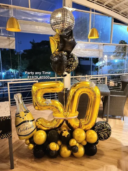 A 50th birthday balloon bouquet with a champagne bottle and disco ball foil balloons. This is a fun and festive centerpiece for a party.