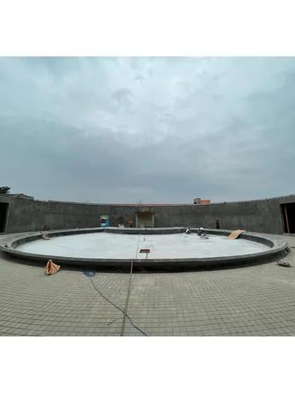 The sunken court of the memorial during the concrete pouring phase, with workers smoothing the surface.