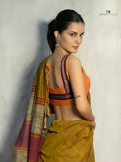 This Khadi cotton saree, paired with a vibrant orange blouse, is your best pick for sunny days. The back tie-up detail on the blouse adds a modern touch to this classic look.