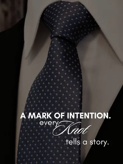 A tie is more than a formality; it is a mark of intention. This close-up of a perfectly knotted navy blue tie with subtle white polka dots illustrates our belief that every detail, no matter how small, contributes to the story your style tells.