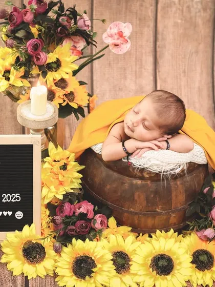 Welcoming baby Aviraj with a burst of sunshine. This newborn is nestled in a wooden bucket surrounded by bright sunflowers, with a letterboard announcing his arrival.